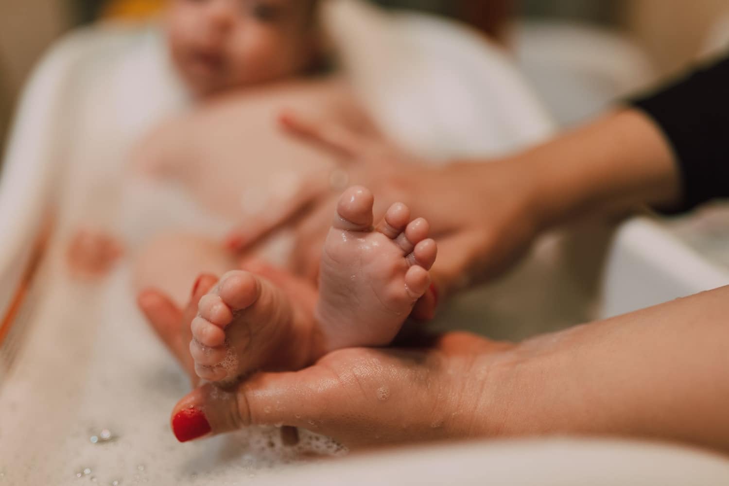 A parent gently bathing their baby
