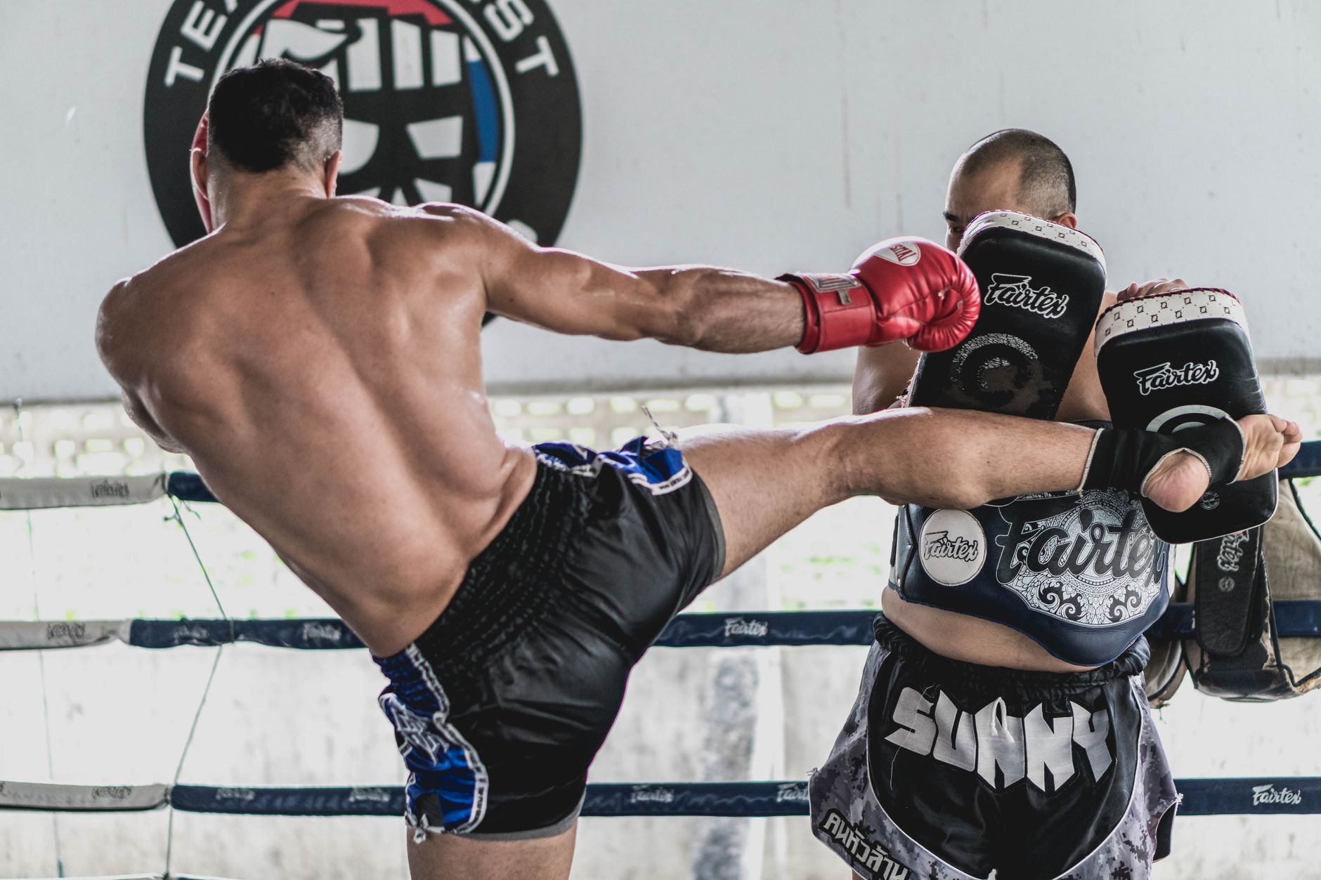 A coach holding pads for a member during a Muay Thai class at Clinch Singapore