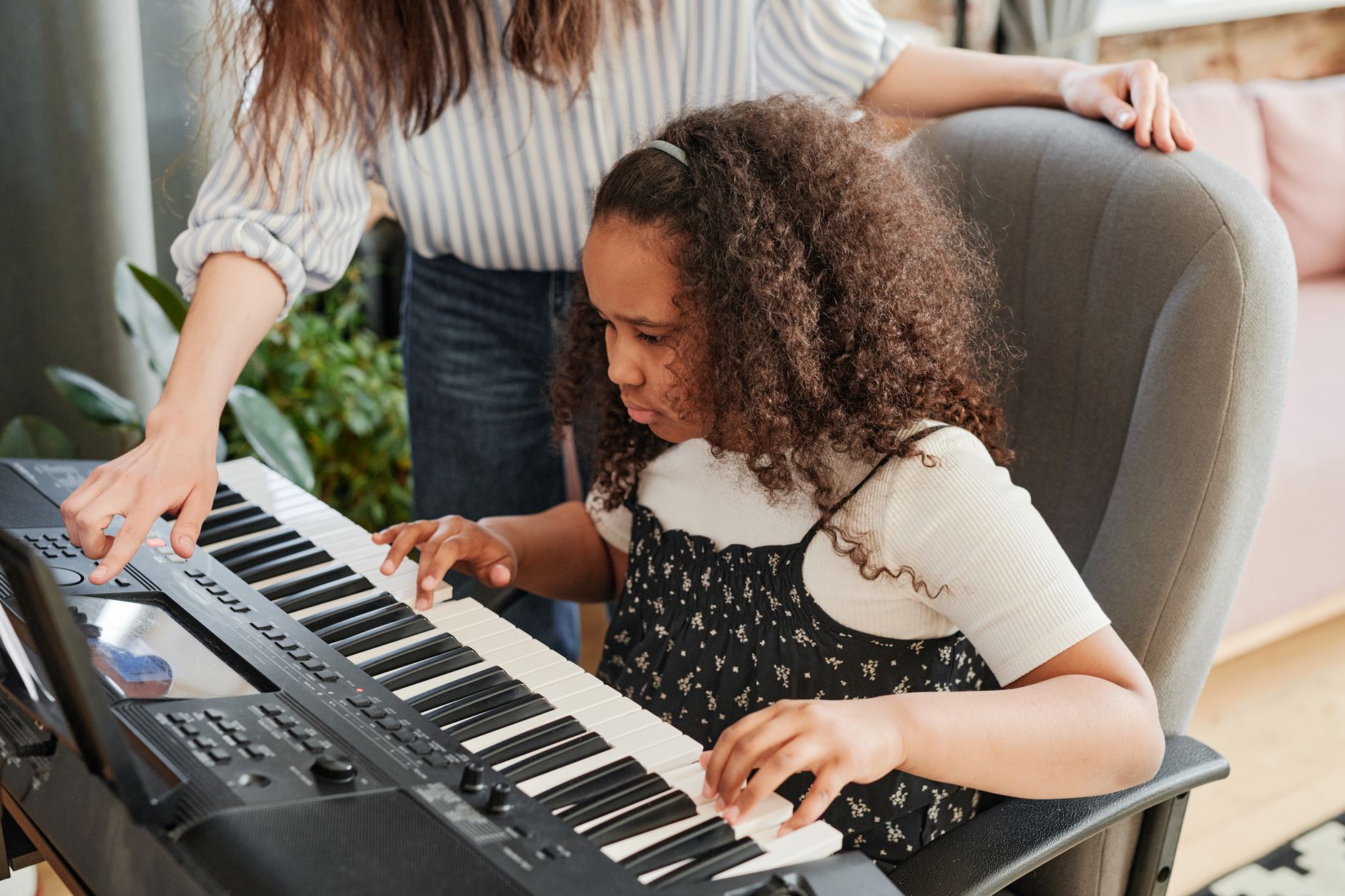 A teacher guiding a young student at the keyboard at Crescendo Music School