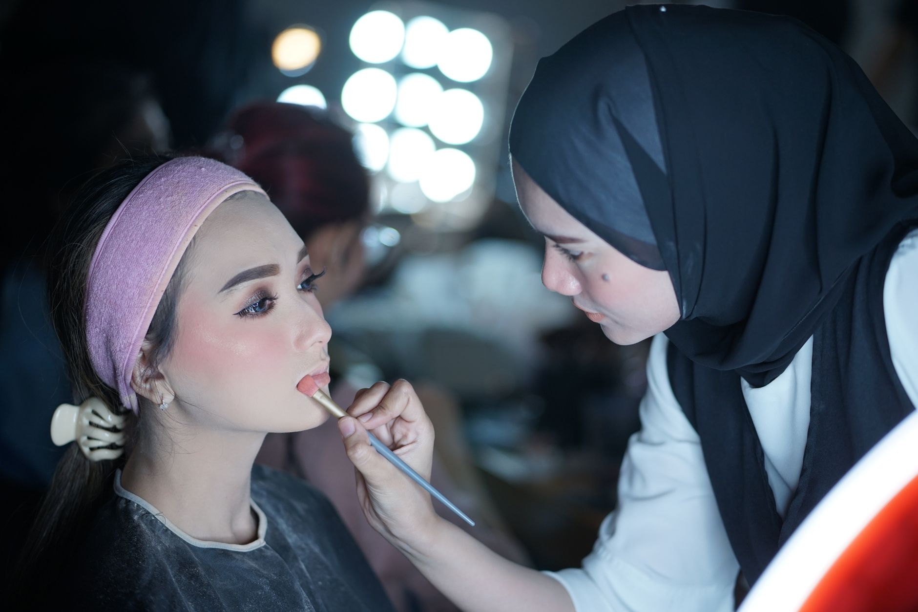 A Maison Belle tutor guiding a student through a makeup look on a model