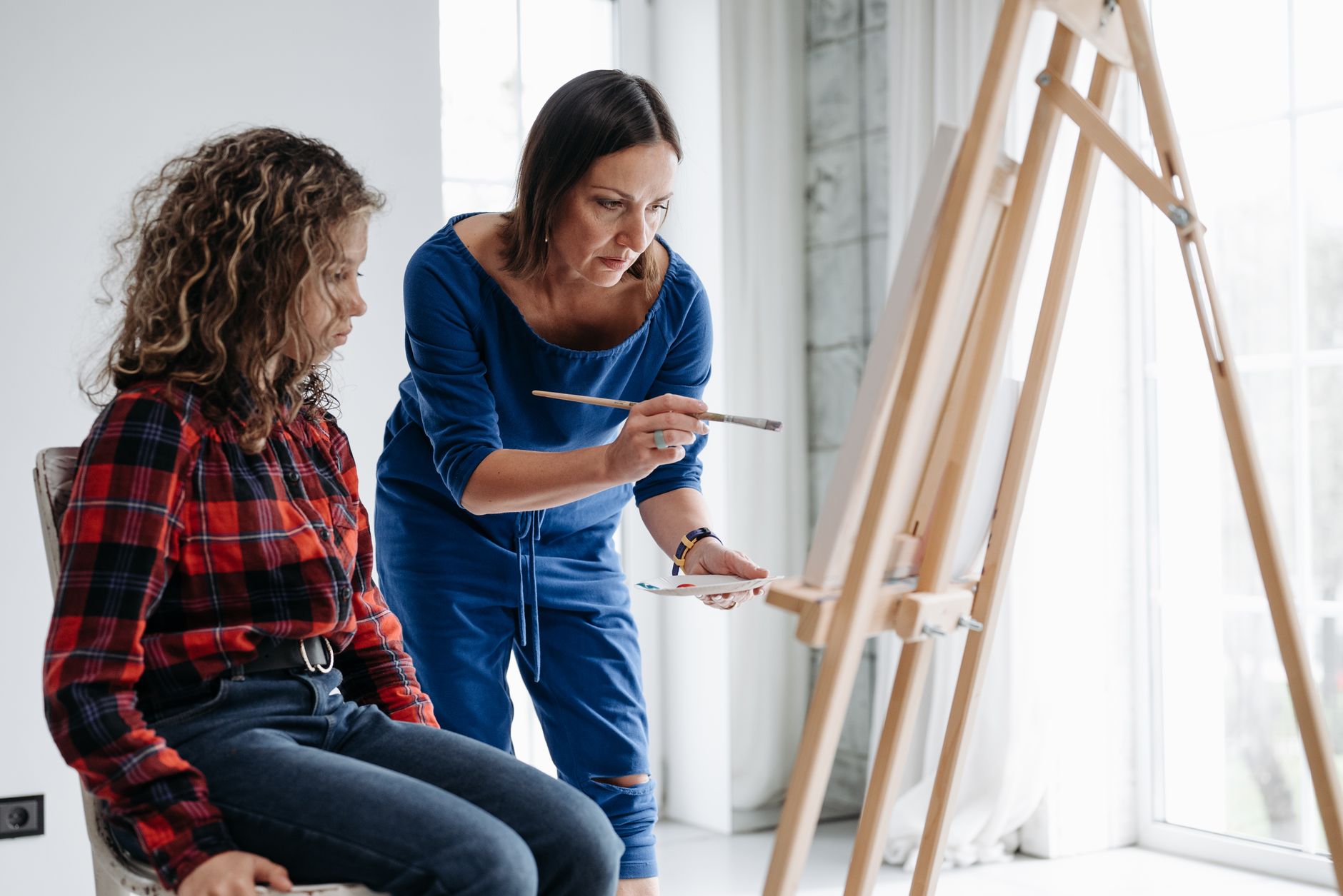 A tutor helping a student paint