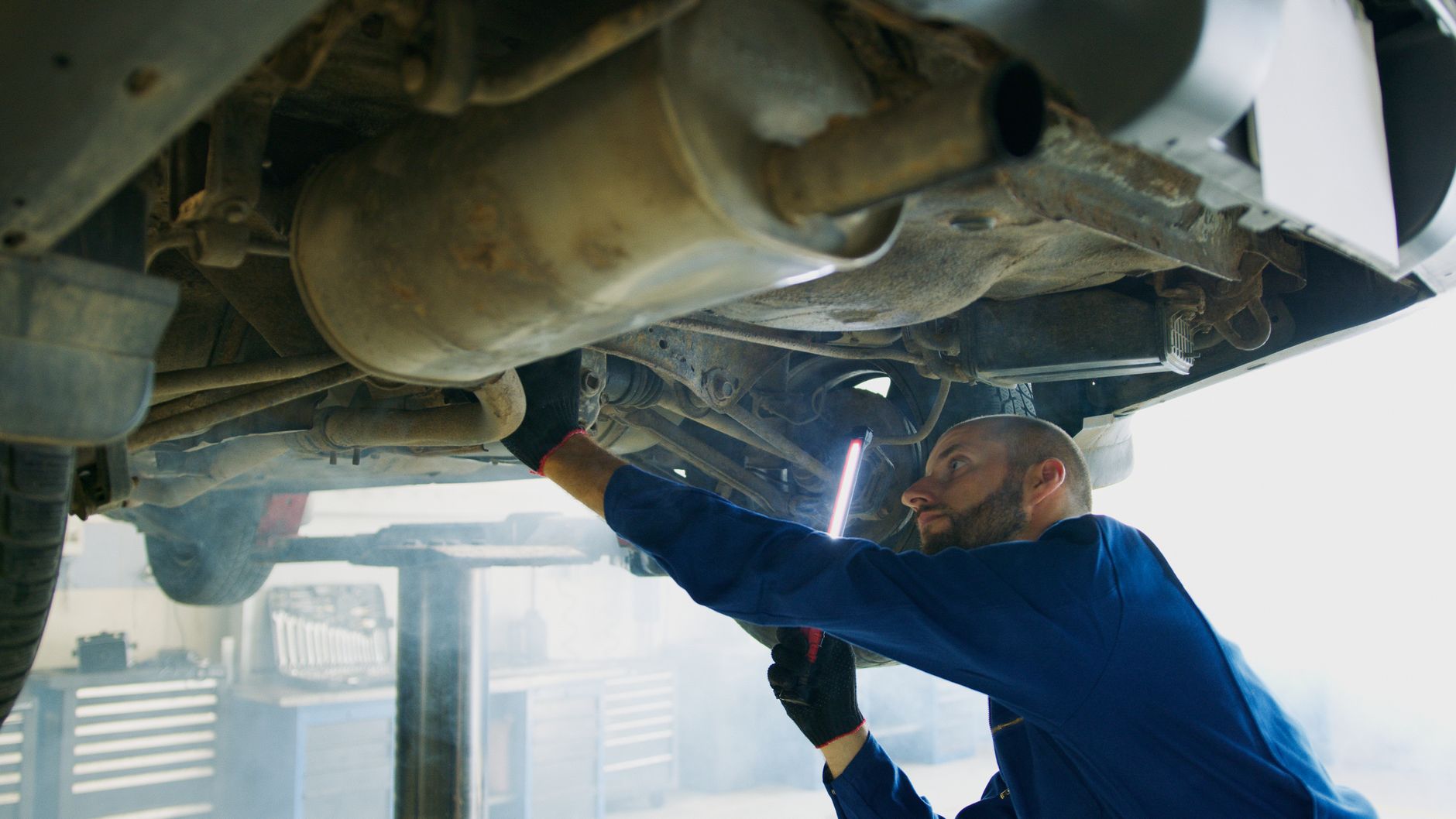A Revline technician working under a car on the lift
