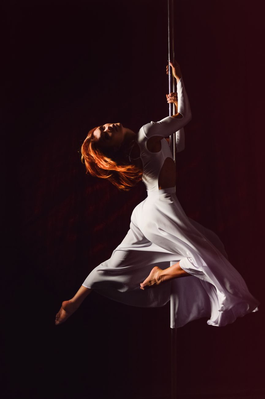A pole dancer mid-spin in the low-lit Suspend studio in Kallang, Singapore
