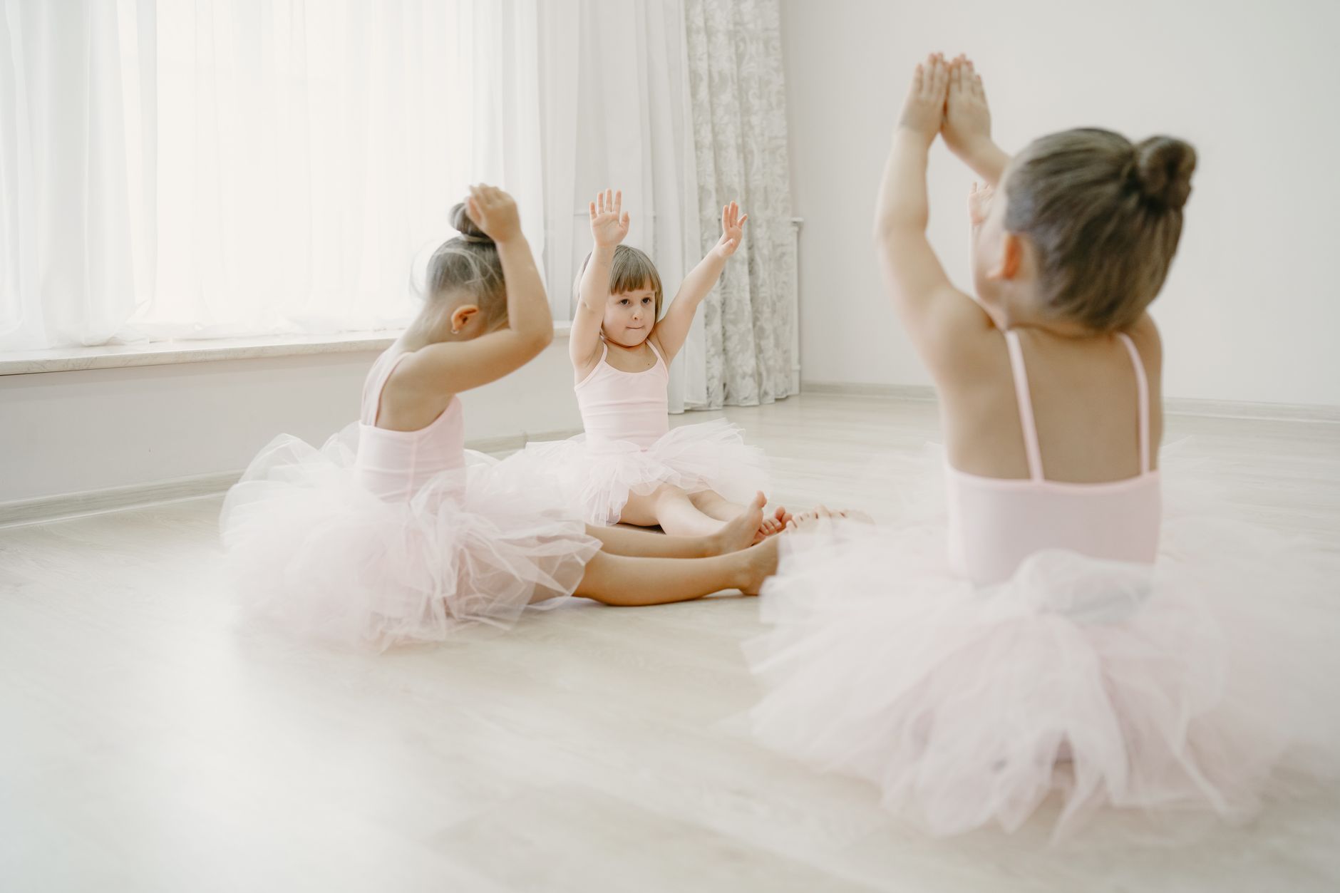Young children in a bright Singapore dance studio mid-twirl during a class